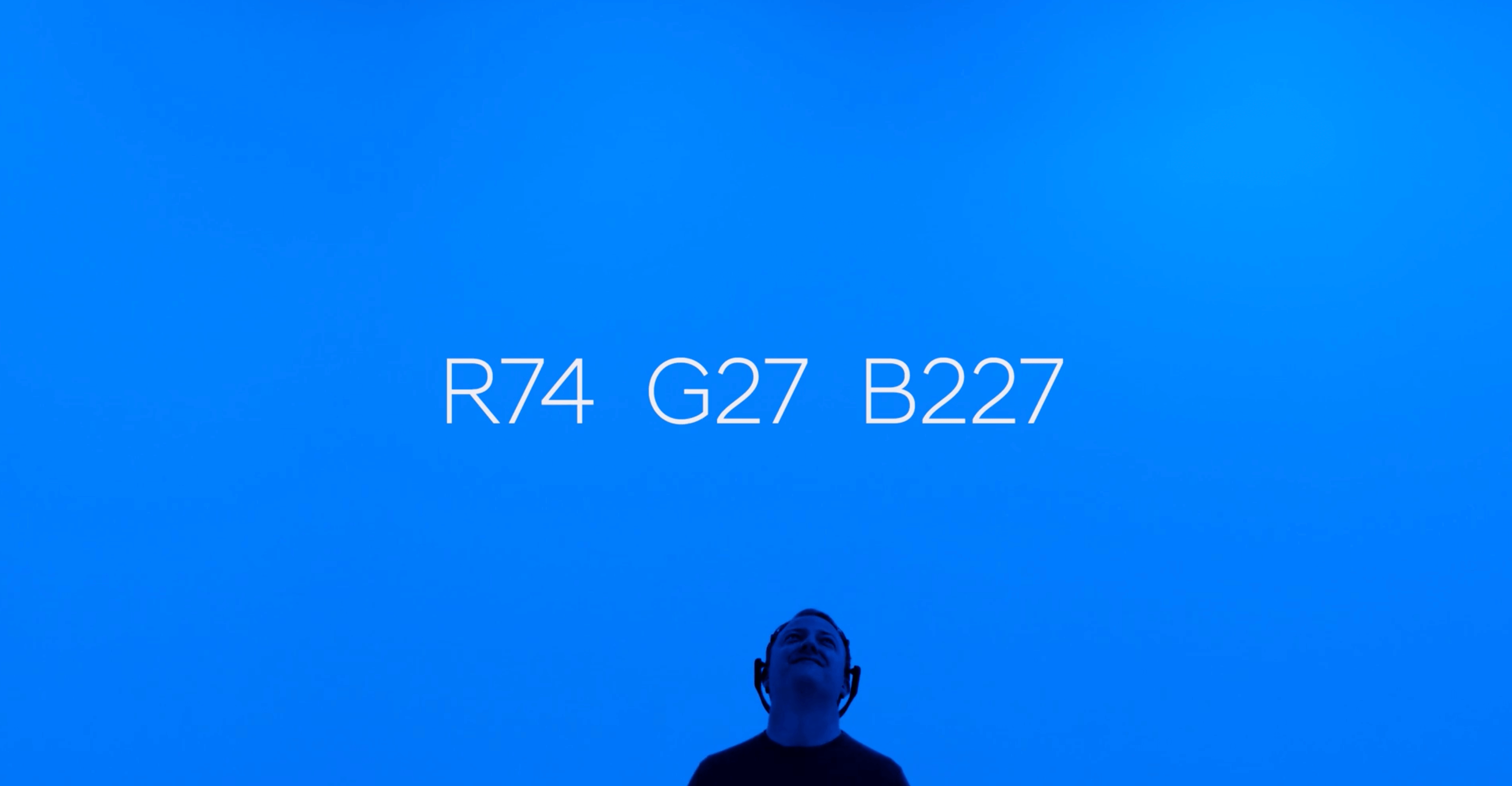 man looking up at blue background with the code r74, g27, b227