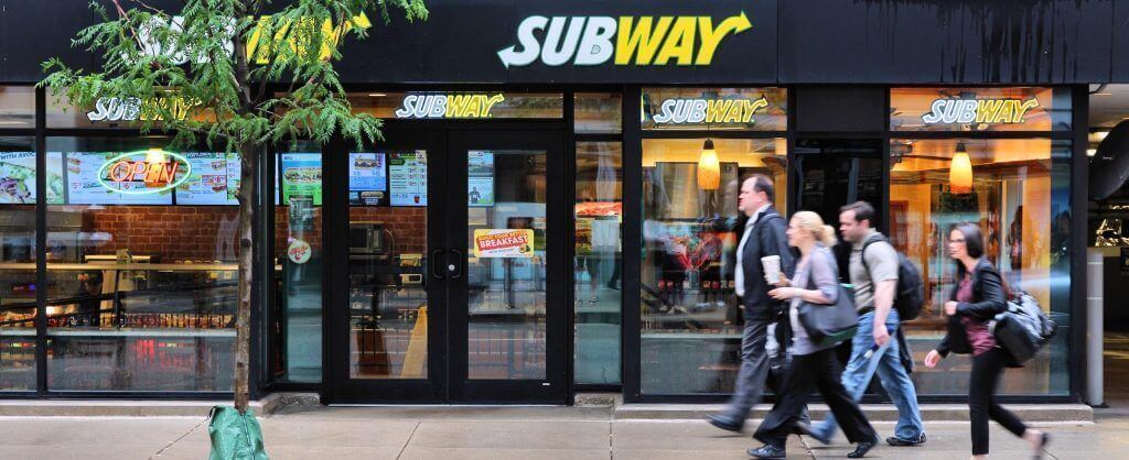 people walking past a subway store