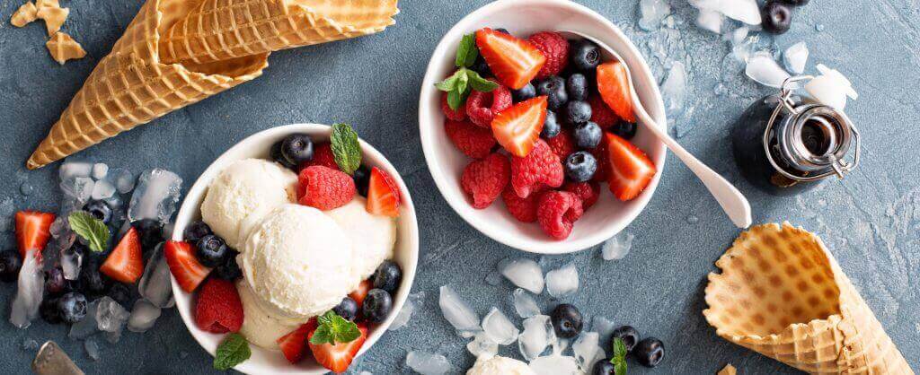 fruit, ice cream, and waffle cones on table with ice cubes