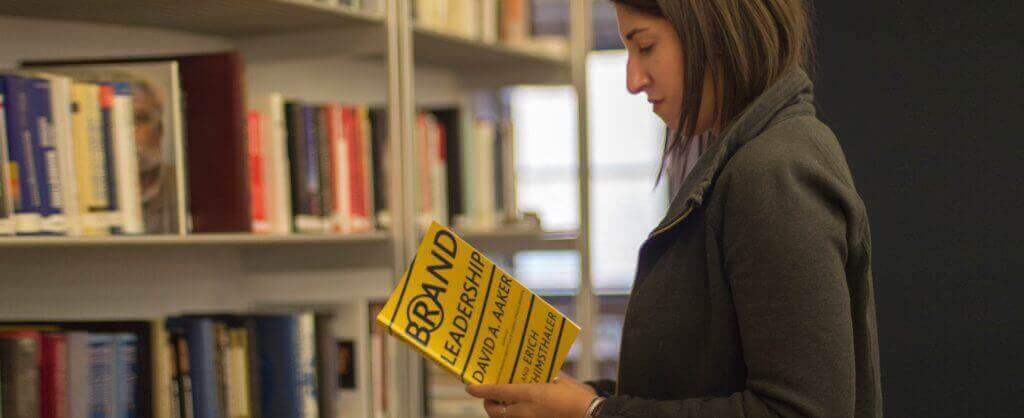 woman reading brand leadership book in library