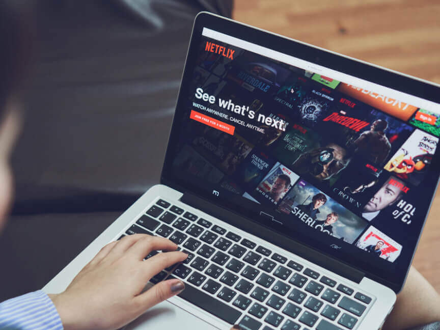 eine Person benutzt einen Laptop mit Netflix auf dem Bildschirm