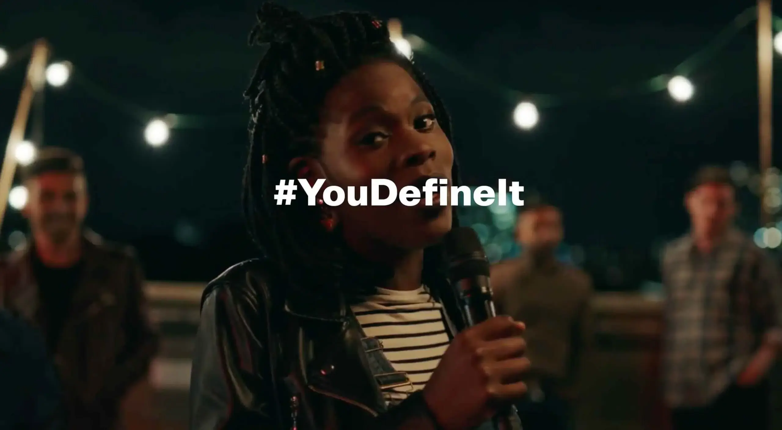 Woman singing into a microphone with the text #youdefineit