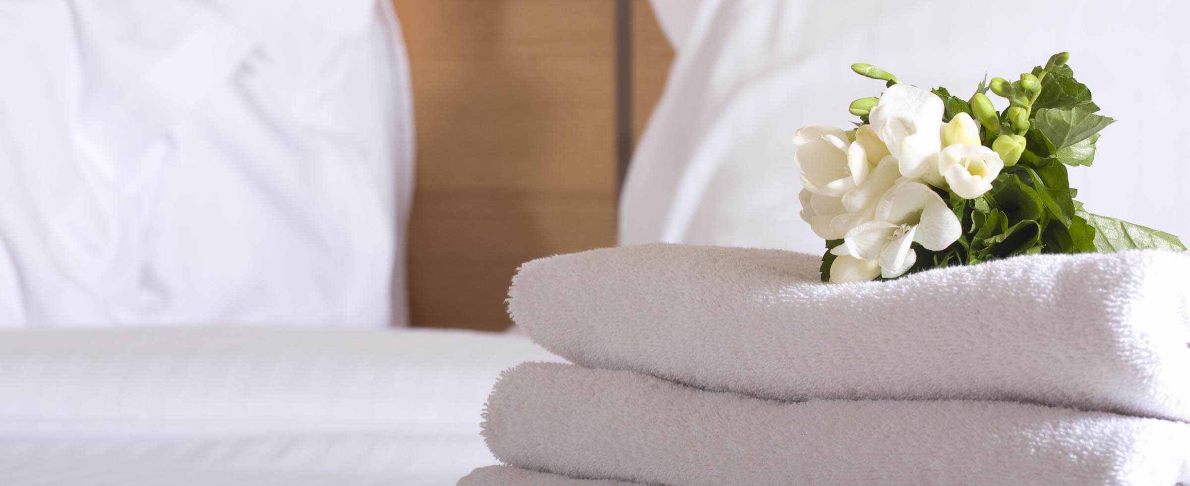 towels and flowers on bed in hotel