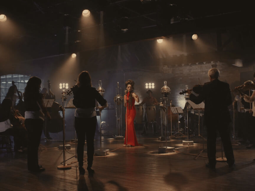 a woman in a red dress singing into a microphone on a dark stage