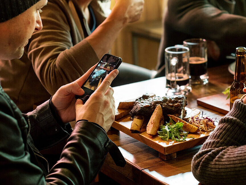 People taking a picture of food that arrived at a restaurant
