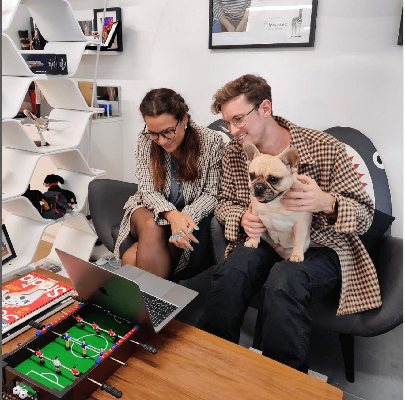 A man and a woman showing their pug puppy on a virtual meeting while working together in an office