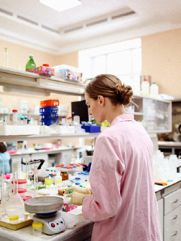 A female scientist working wearing a pink lab coat working inside a laboratory.